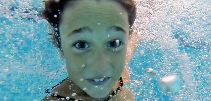 Niño disfrutando de un chapuzón en una piscina de un hotel de Playa Hoteles