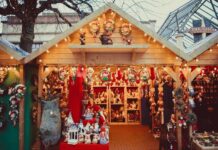 Mercadillo navideño en una caseta con productos artesanos en tonos rojos y luces de fondo.