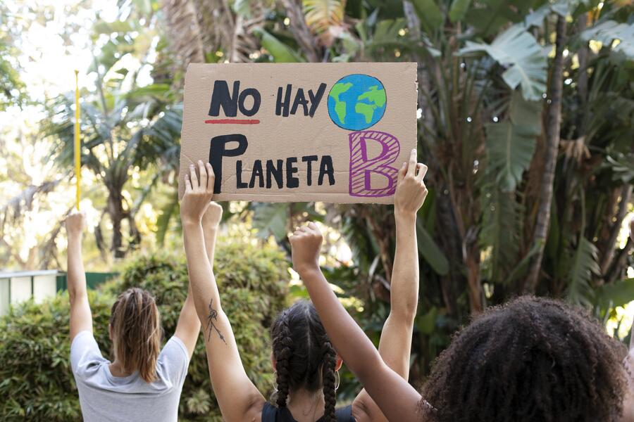 Mujeres de espaldas con pancartas en las manos protestan contra el cambio climático